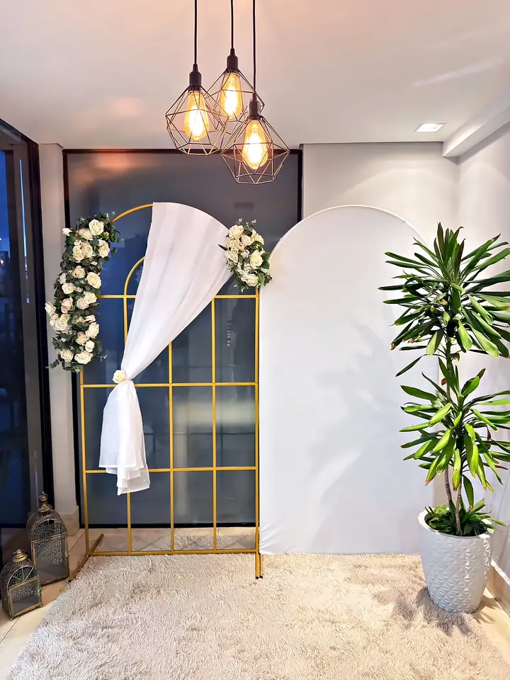 Arco dourado com cortina branca, flores e pendentes