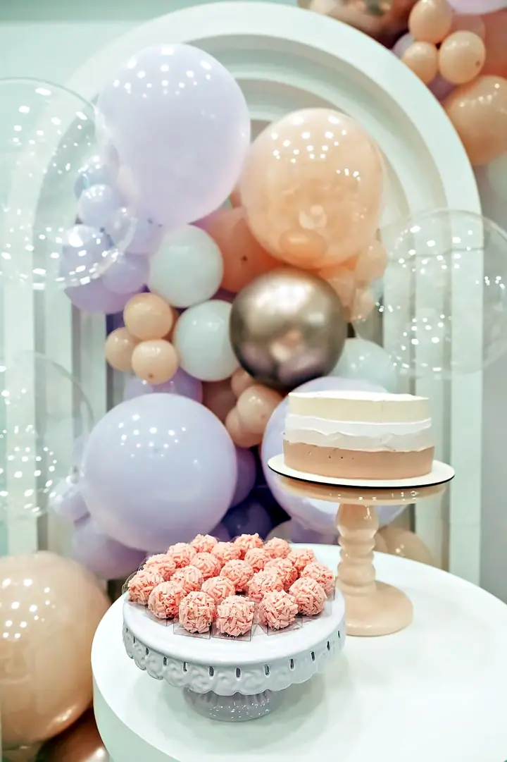 Detalhe do bolo e dos doces com balões em tons pastel